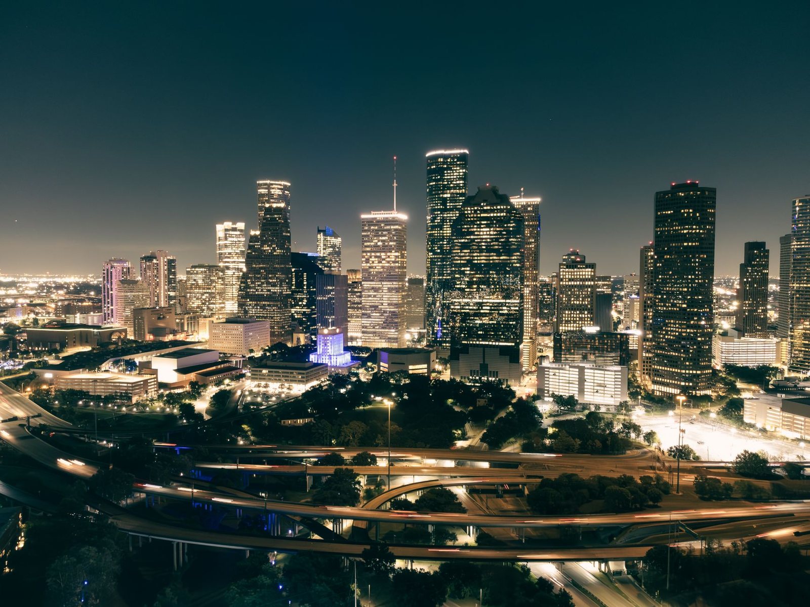 Downtown Houston skyline lit up at night above the freeway interchanges west of downtown
